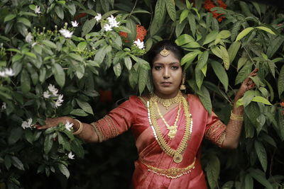 Portrait of woman standing against plants