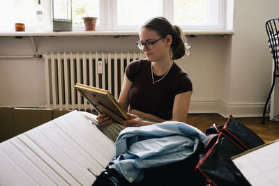 Smiling woman looking at frame while unpacking at home