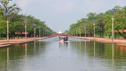 Man in canal amidst trees against sky