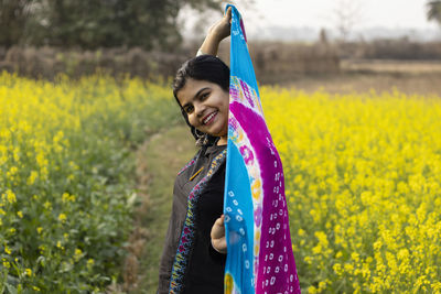 Portrait of smiling young woman standing on field