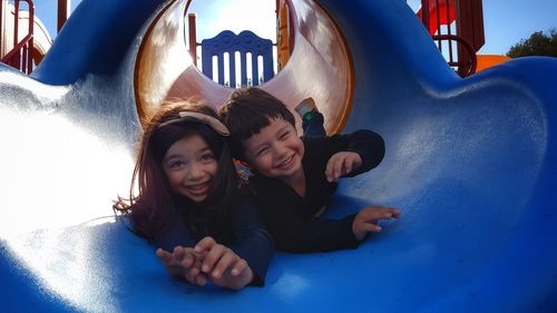 Siblings playing on slide at park