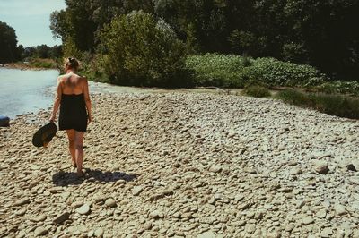 Rear view of shirtless woman walking on beach