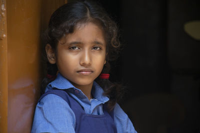 Portrait of girl wearing school uniform standing by door