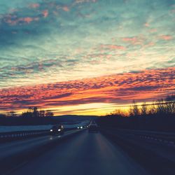 Cars on road against sky during sunset