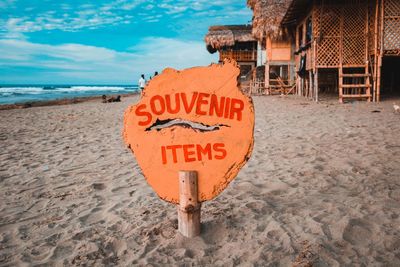 Information sign on beach against sky