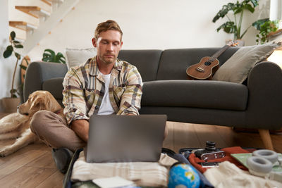 Young friends using laptop while sitting on sofa at home