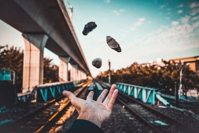 Close-up of hand on railroad track against sky