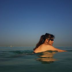 Woman swimming in sea against clear sky