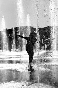 Low section of woman standing in swimming pool against sky