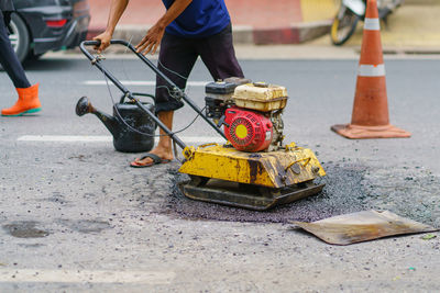 Road repair, workers and machinery are working paved road with asphalt and gravel, 