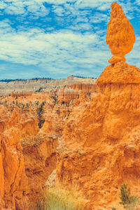 Rock formations on landscape against cloudy sky