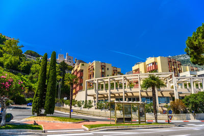 Street by buildings against blue sky