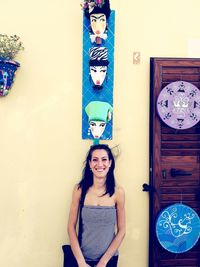 Portrait of a smiling young woman standing against wall