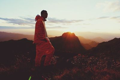 Man standing on mountain against sky during sunset