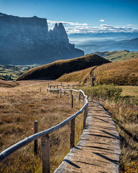 Footpath leading towards mountains against sky