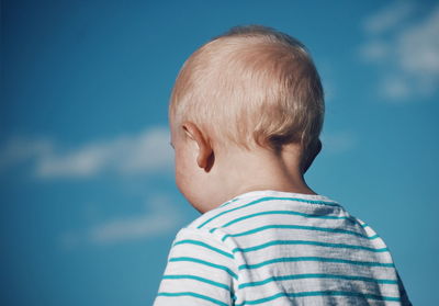 Close-up of boy against blue sky