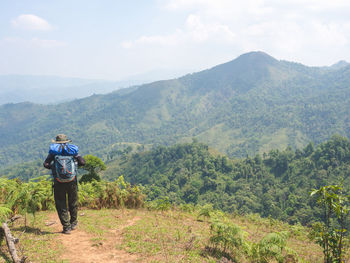 Rear view of man standing on mountain against sky