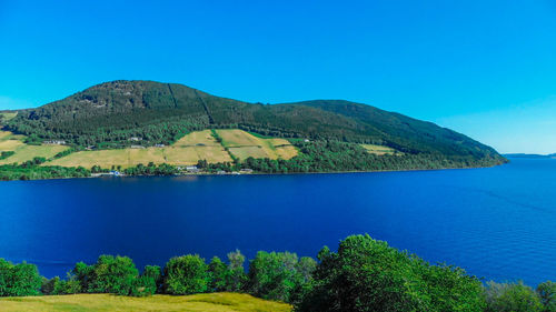 Scenic view of sea and mountains against clear blue sky