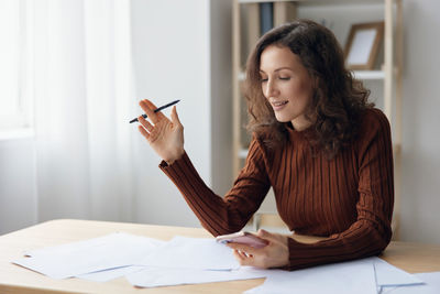 Young woman using mobile phone while sitting on table