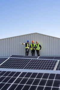 Engineers discussing about solar panels on sunny day