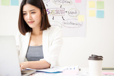 Portrait of young woman using phone on table