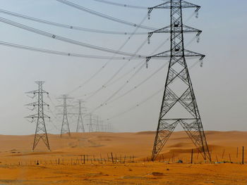 Low angle view of electricity pylon on field against clear sky