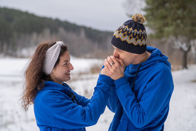 Outdoor happy couple in love posing in cold winter weather. a man and a woman in blue hoodies. 