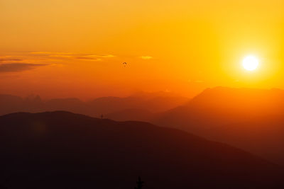 Scenic view of silhouette mountains against orange sky