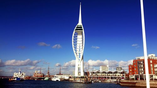 Spinnaker tower by harbor against blue sky