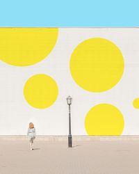 Rear view of woman walking against patterned wall