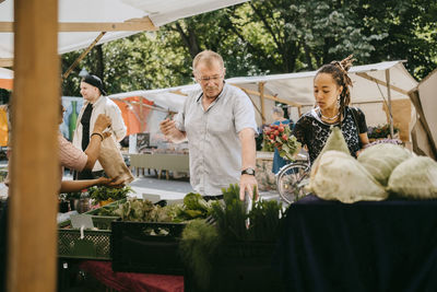 Customers buying organic vegetables from market