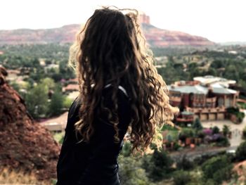 Rear view of woman standing on mountain against sky