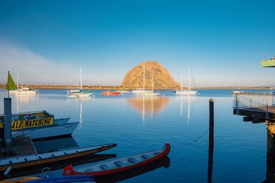 Sailboats moored in sea against clear blue sky