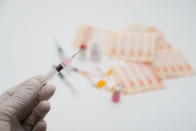 Cropped hand of doctor holding syringe over white background