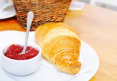 Close-up of croissant and jam in plate on table