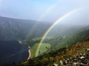 Scenic view of rainbow over mountains against sky