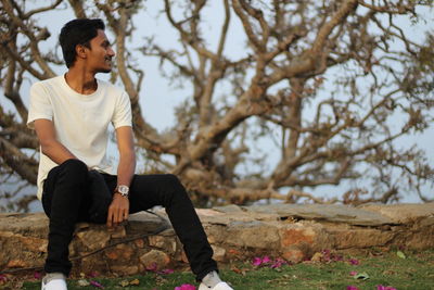 Young man looking away while sitting on land