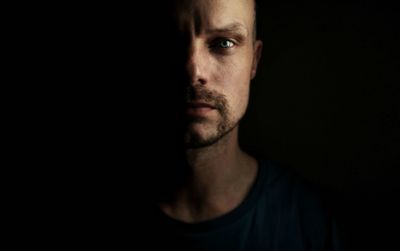 Close-up portrait of young man against black background