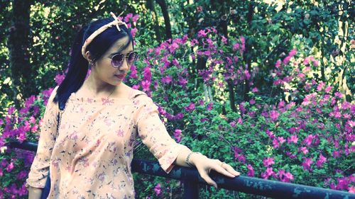 Young woman standing by purple flowers at park