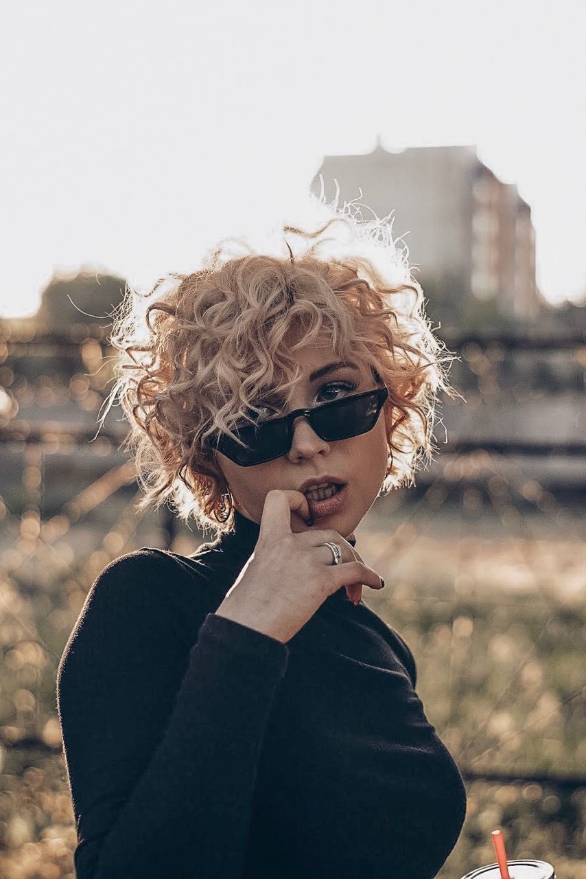 PORTRAIT OF MAN WEARING SUNGLASSES STANDING AGAINST WALL