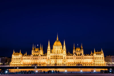 View of illuminated building by river at night