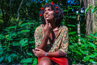 Young woman looking away while sitting in plants