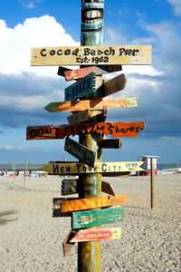 Information sign on beach against sky