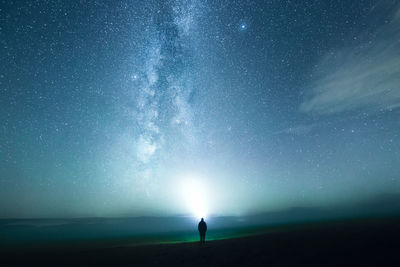 Rear view of woman standing against sky at night