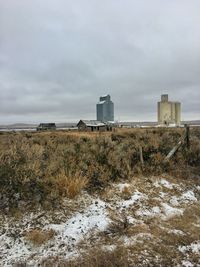 Abandoned building on field against sky during winter