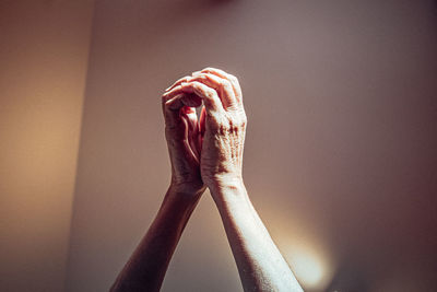 Cropped image of person holding hands against wall