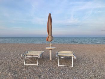 Empty chair on beach against sky