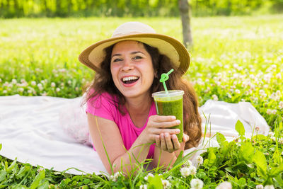 Portrait of a smiling young woman drinking glasses outdoors