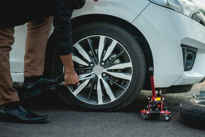 Low section of man standing by car