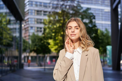 Portrait of young woman standing in city